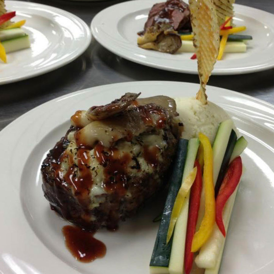 Plated steak with sauce, mashed potatoes, veggies, and a crisp—perfect for special events at Rochester International Event Center.