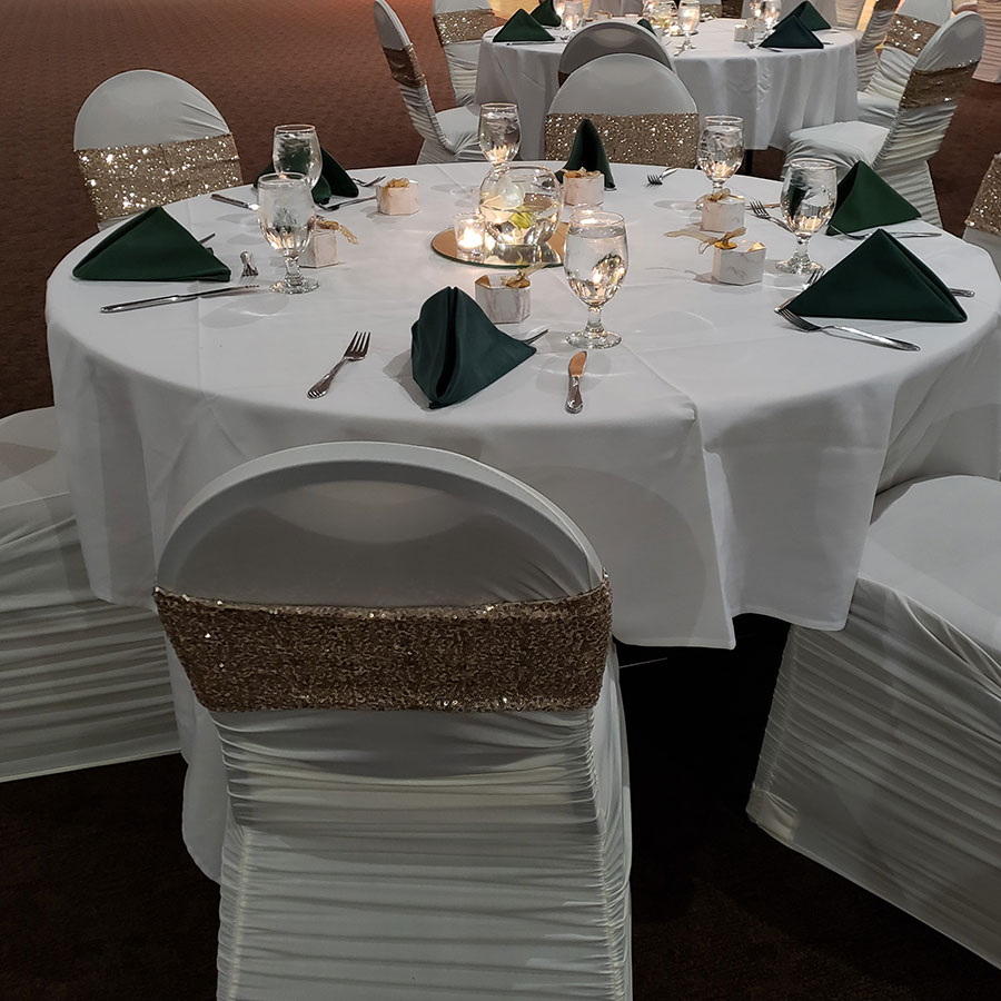 Round table set for Rochester Event Center summer weddings with white linens and gold chair sashes.