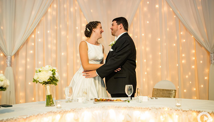 A bride and groom smile at each other by a decorated table at Rochester Event Center.