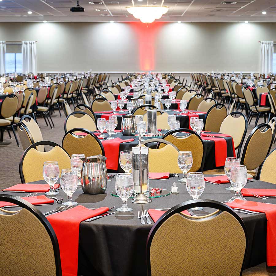 Large banquet hall at Rochester Event Center with round tables, red napkins, and black tablecloths.