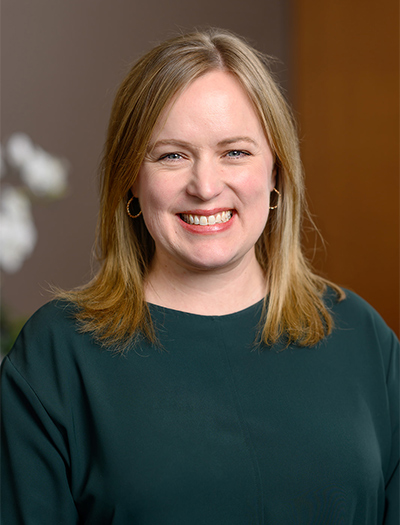 Smiling woman with blonde hair and hoop earrings at the About Rochester Event Center, indoors.
