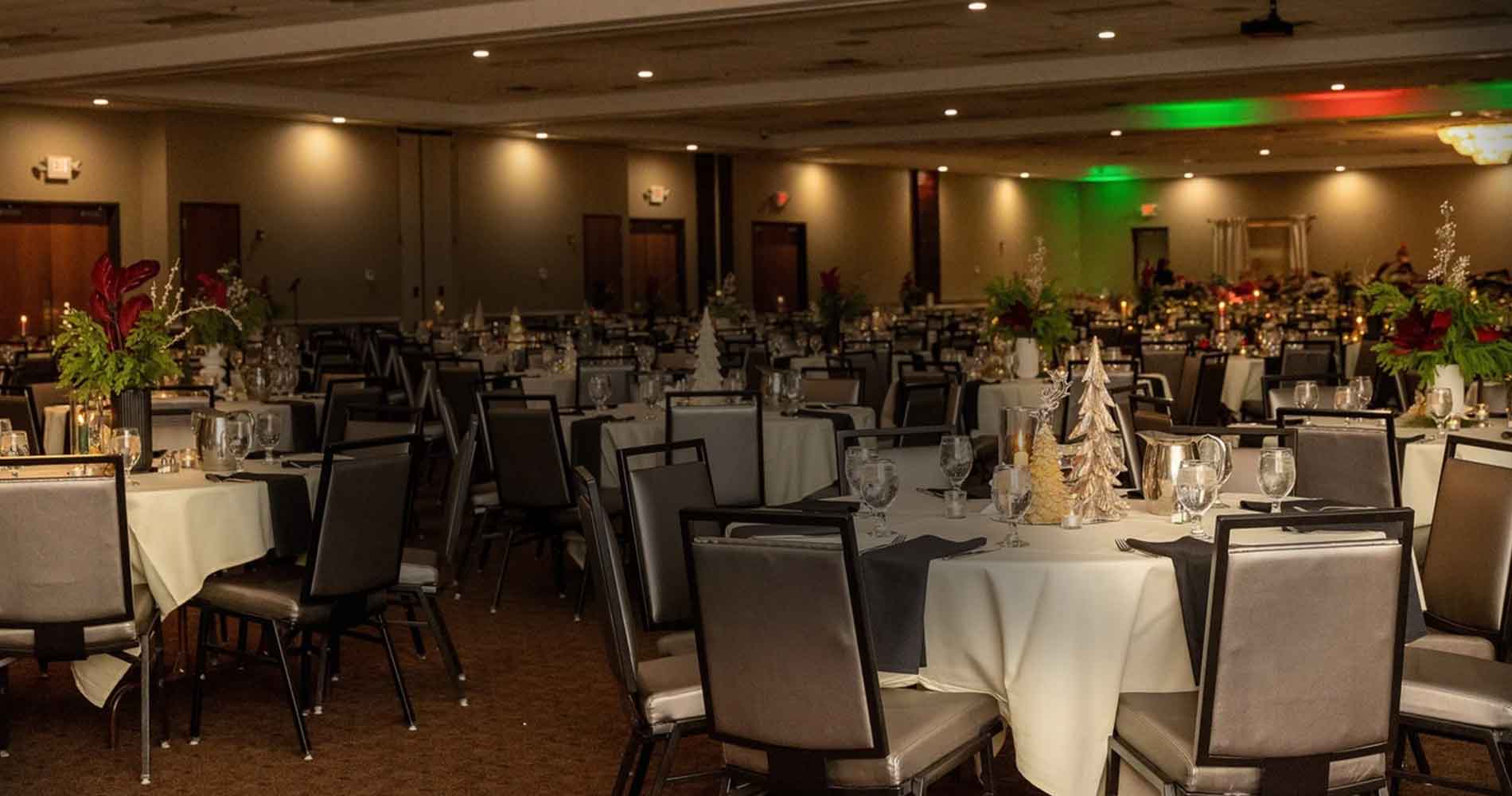 Elegant banquet hall with round tables set for an event, decorated with centerpieces and glasses.